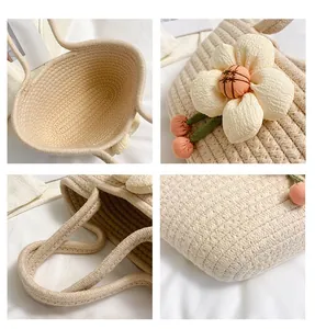 Details einer beige gewebten Handtasche mit Blumendekor und verstärkten Griffen