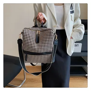 Détail d'un sac à dos pied-de-poule avec finitions en cuir noir et garnitures dorées