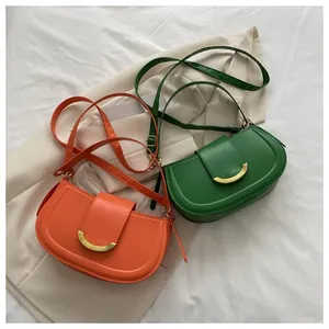 Detail of orange and green saddle bags with crescent metal buckle on smooth PU leather
