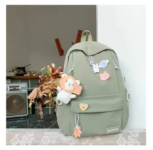 Primer plano de mochila escolar verde claro con insignias y colgante de león de peluche