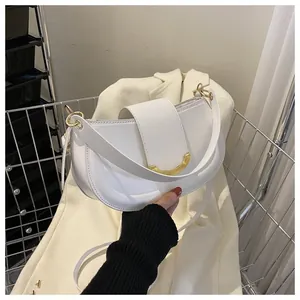 Detailed close-up of white saddle bag with U-shaped gold hardware and fine leather texture