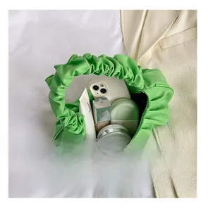 Interior view of emerald green pleated cloud bag showing storage for cosmetics and phone