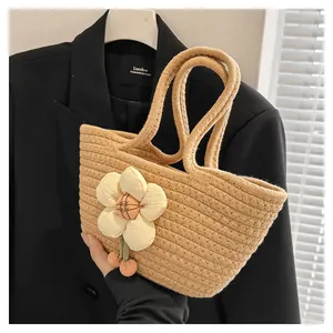 Detailansicht der beigen Flecht-Handtasche mit weißer Blume und roten Kirschen-Anhängern