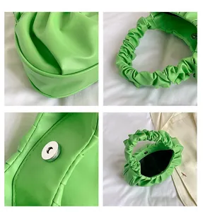 Detail view of bright green ruched cloud bag showing pleated handle and magnetic clasp