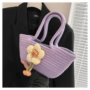 Detail einer lila gewebten Handtasche mit Stoffblumen-Anhänger und weicher Baumwolltextur