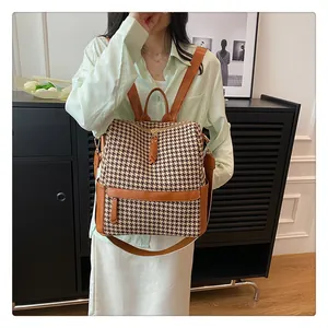Détail d'un sac à dos rétro à motif pied-de-poule avec finitions en cuir brun