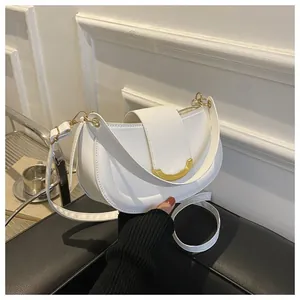 Detail of white saddle bag showing gold U-shaped hardware and dual detachable straps