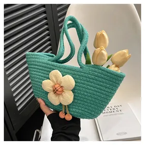 Detail der minzgrünen gewebten Tasche mit 3D-Blume und orangefarbenen Pompon-Anhängern