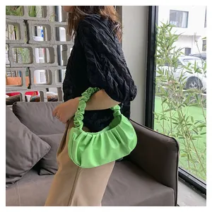 Detail of light green ruched dumpling bag featuring soft pleated faux leather texture
