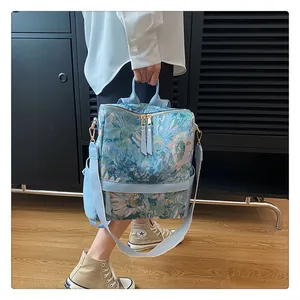 Détail d'un sac à dos à fleurs bleues montrant le tissu jacquard et les finitions dorées