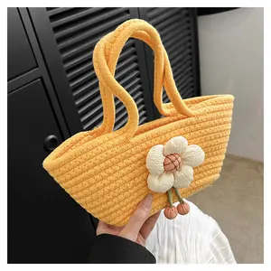 Detail der gelben Strickhandtasche mit großer 3D-Stoffblume und rosa dekorativen Perlen