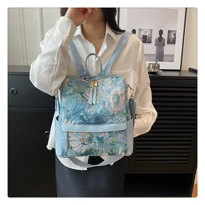 Détail du tissu jacquard floral bleu clair et des bretelles en cuir d'un sac à dos