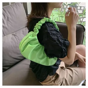 Detail of lime green ruched cloud bag showing pleated texture and matching shoulder strap