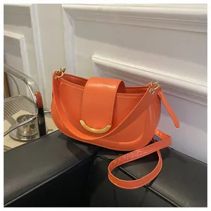 Macro view of bright orange saddle bag with decorative gold U-shaped metal buckle