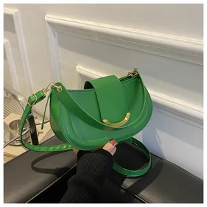 Detailed view of emerald green saddle bag with golden crescent buckle and leather strap