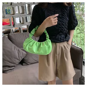 Chic bright green ruched cloud bag shown styled with a black top and khaki shorts