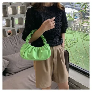 Close-up of bright green pleated cloud bag with textured handle and vibrant PU leather finish