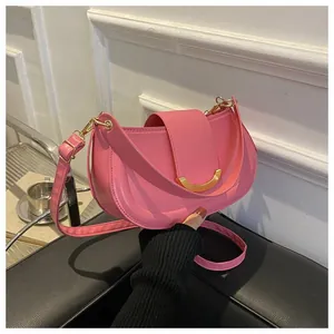 Close-up of pink crescent saddle bag featuring gold metal buckle and leather strap