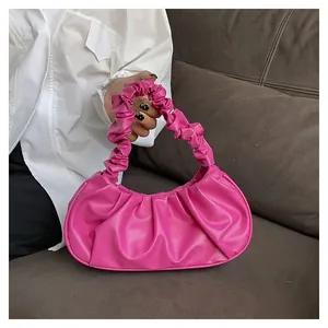 Detail of rose pink pleated handbag showing soft PU leather texture and crescent shape