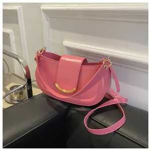 Close-up of pink leather saddle bag featuring a stylish crescent-shaped gold metal buckle