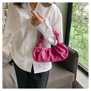 Detail of fuchsia pleated cloud bag showing glossy leather texture and stylish ruched handle