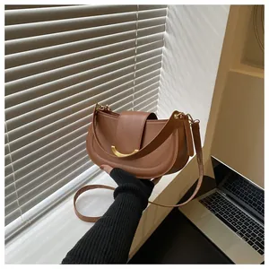 Detailed close-up of brown saddle bag with golden crescent buckle and smooth leather