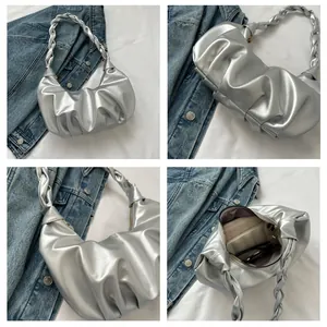 Close-up of silver pleated crescent bag with woven handle and interior storage capacity