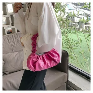 Detail of fuchsia pleated cloud bag showing soft PU texture and matching shoulder strap