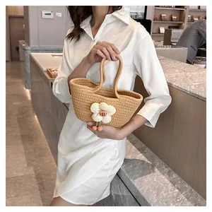Detail der beige gewebten Tragetasche mit 3D-Blumenanhänger und Doppelgriffen