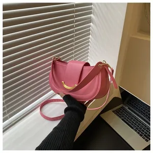 Macro shot of pink crescent saddle bag featuring gold clasp and smooth synthetic leather