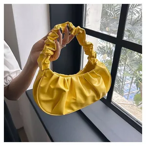 Detail of a bright yellow pleated cloud bag with soft PU leather texture and curved design