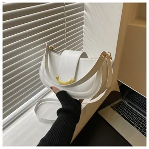 Detail of white saddle bag showing gold metal buckle and neat stitching on high-quality faux leather