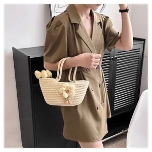 Detailaufnahme einer beigefarbenen geflochtenen Handtasche mit Stoffblumen an einem Modell