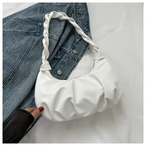 Detail of white pleated shoulder bag with braided strap on a blue denim background