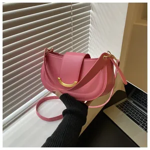 Detailed shot of a pink leather saddle bag with a crescent gold metallic buckle clasp
