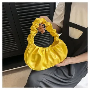 Detail of a bright yellow pleated hobo bag featuring a cloud-like ruched handle