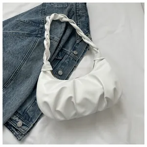 Detailed view of a white ruched cloud bag with a braided handle on blue denim fabric