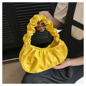 Detail of a bright yellow pleated PU leather dumpling bag with textured top handle