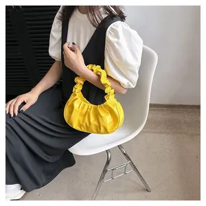 Close-up of bright yellow pleated cloud bag with textured handle on model's shoulder