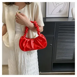 Detail of red ruched hobo bag with ruffled handle in glossy PU leather finish