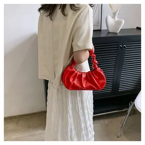 Detail of red ruched cloud handbag showing glossy texture and shoulder carry style