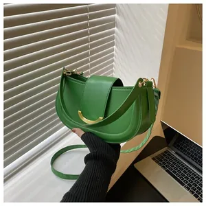 Detail of green leather saddle bag featuring a gold metal clasp and adjustable shoulder strap