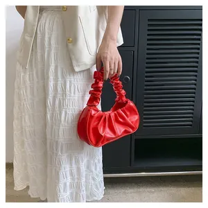 Detail of red ruched cloud bag showing the pleated texture and curved handle design