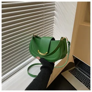 Close-up of a bright green half-moon saddle bag with smooth leather and gold buckle