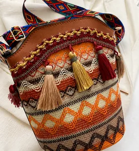Détail du sac seau bohème avec motifs tribaux, pompons colorés et bandoulière tissée