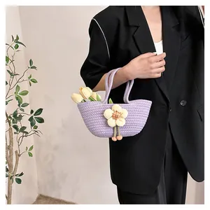 Detail der lila Stricktasche mit cremefarbener Blume und rosa Pompons für Damen