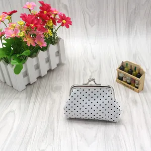 Detailed view of a white canvas coin purse with black polka dots and metal clasp closure