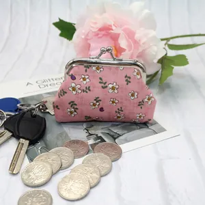 Pink floral fabric coin purse with metal clasp shown with coins and accessories