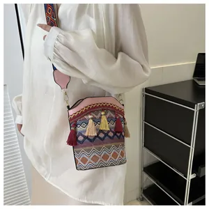 Dettaglio della borsa a secchiello boho con frange colorate e tracolla ricamata etnica