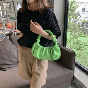 Vibrant green pleated cloud bag shown as a chic shoulder bag in a stylish lifestyle scene